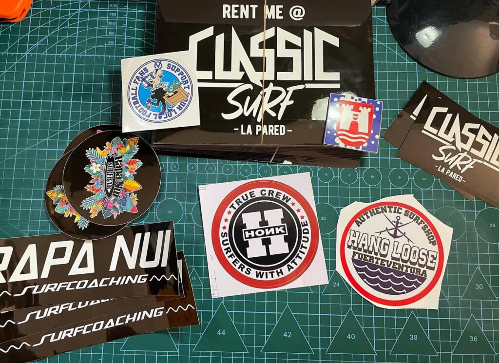 Collection of custom vinyl stickers for various surf brands in Fuerteventura, including Classic Surf and Hang Loose.